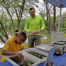 DRBC staff looks on as a fishing derby participant checks out our trays of aquatic critters. Photo by the DRBC.