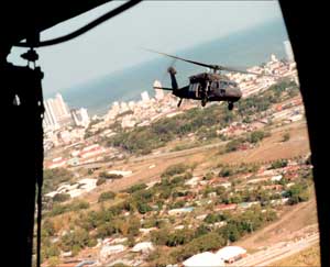 UH-60A Blackhawk flying "loose tail" with the Panama City skyline and the Pacific Ocean in the background.