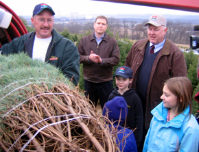 Photo of John Wyckoff baling the tree as Assemblyman Doherty and Secretary Kuperus look on