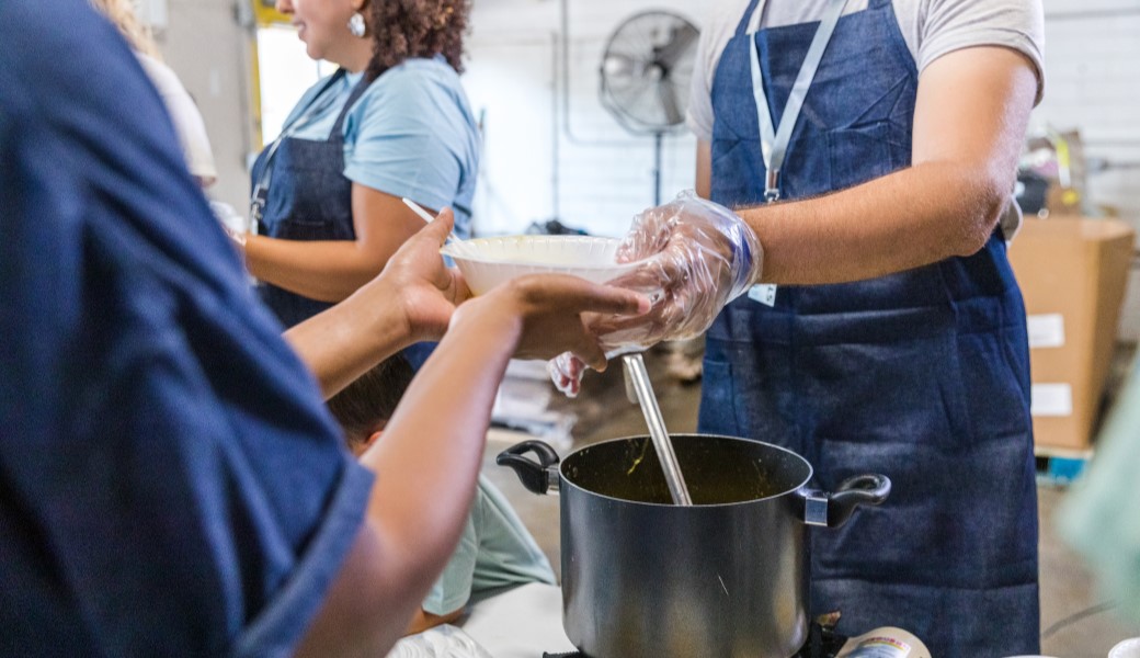 Woman giving food to people on the kitchen