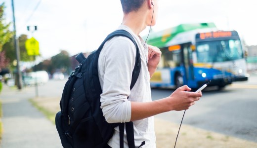 A man with a backpack waiting for a bus outside