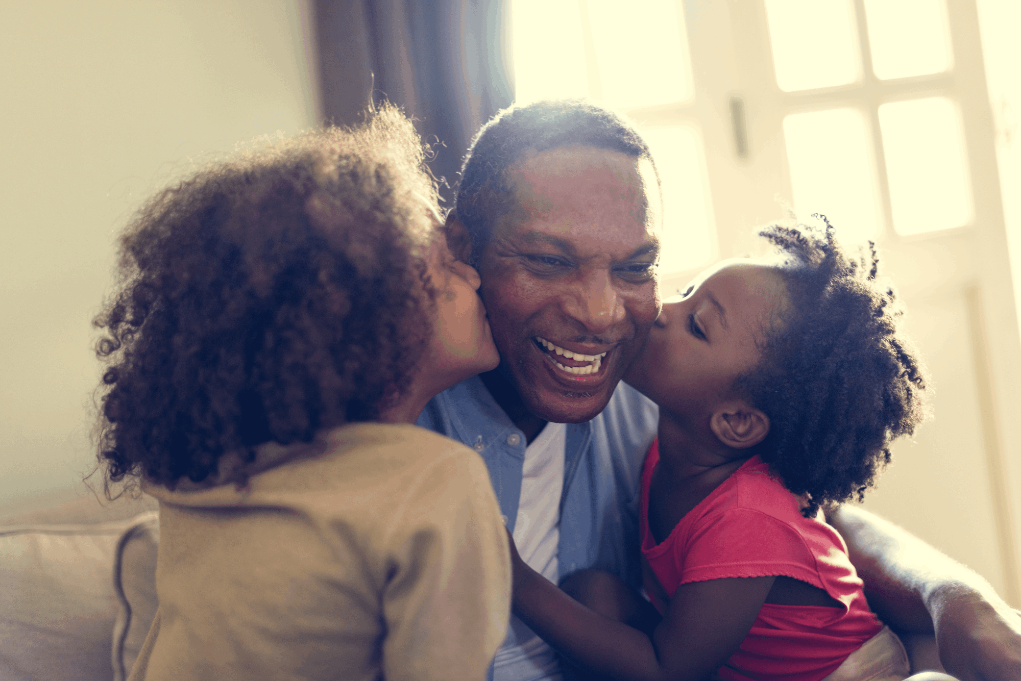 Father being kissed  by 2 young daughters