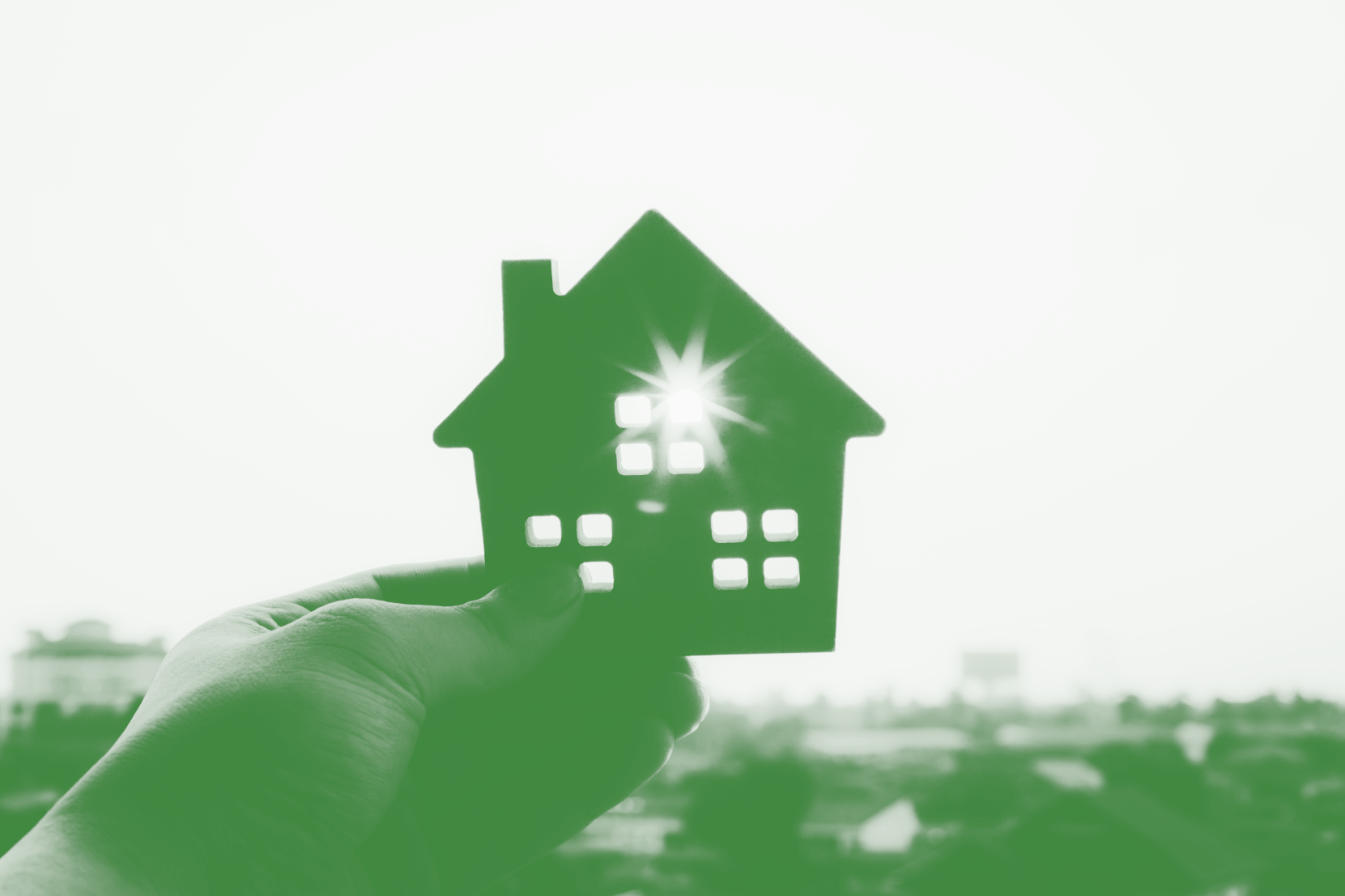 hand holding a home cutout over sunburst