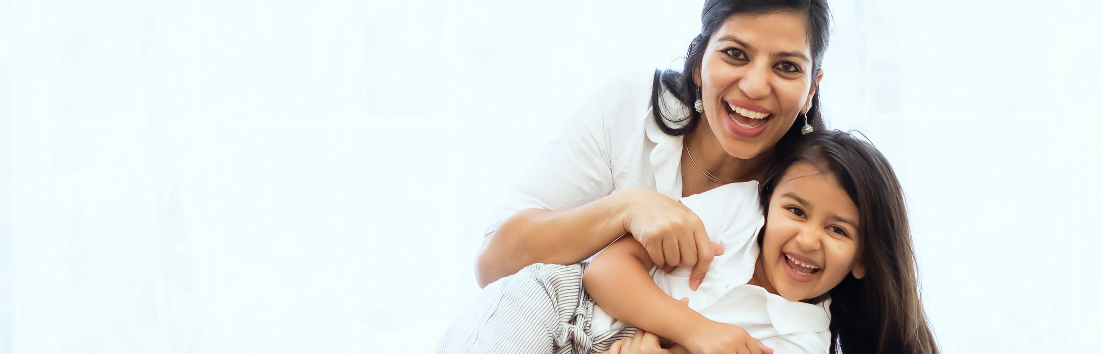 mother holding her daughter playfully smiling