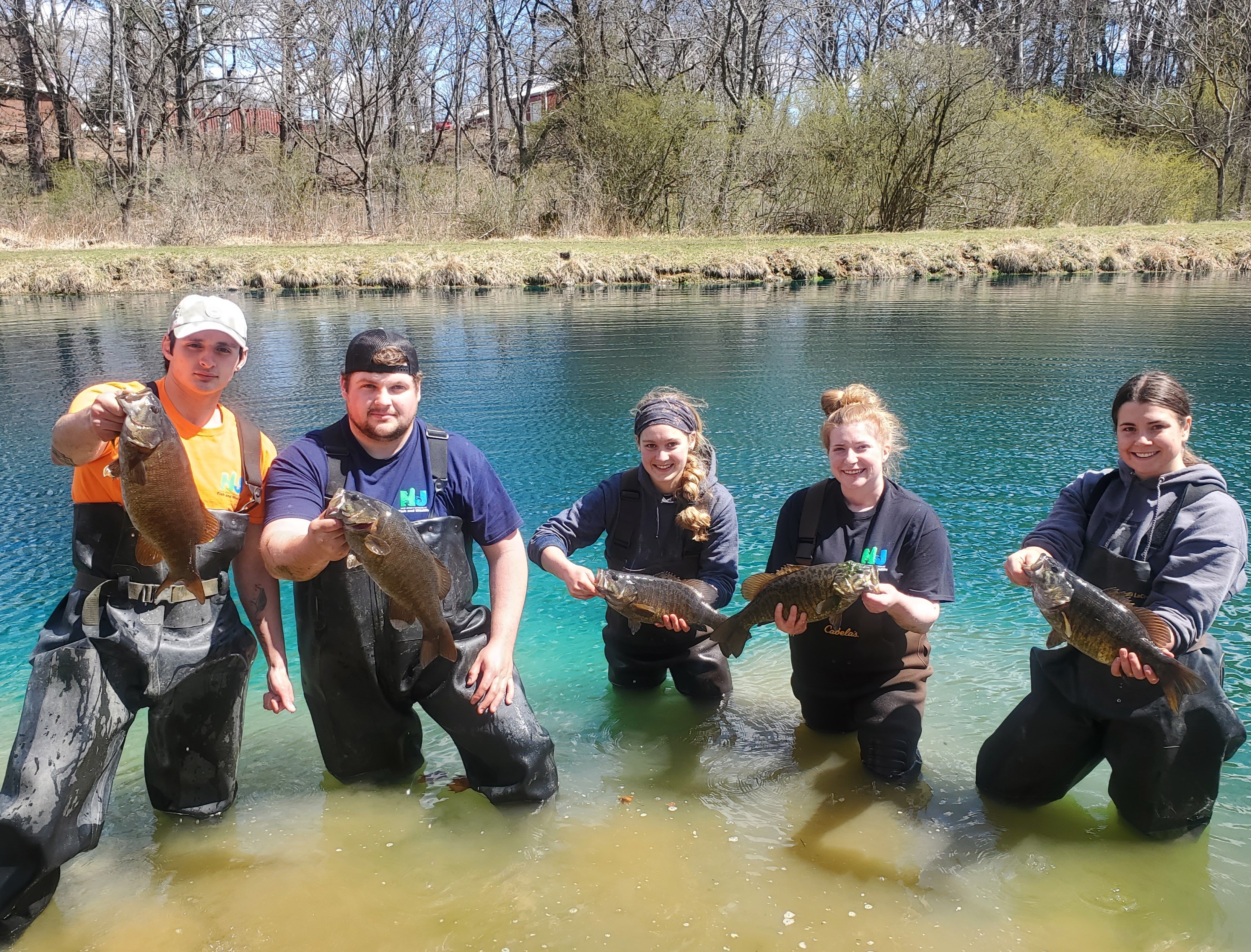 Photo of Young Adults in Water Holding Bass