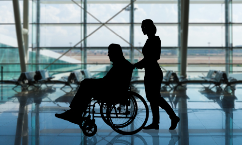 A person in a wheelchair being assisted through an tranportation concourse