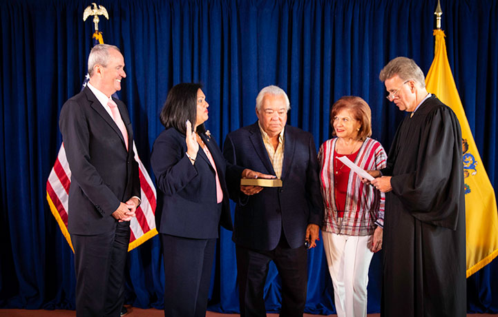 Marlene Caride takes the oath of office to become the first Hispanic Commissioner of the New Jersey Department of Banking and Insurance. She is joined by her parents, Pedro and Norma Caride, and Governor Phil Murphy. Superior Court Judge Mark Nelson administered the oath.