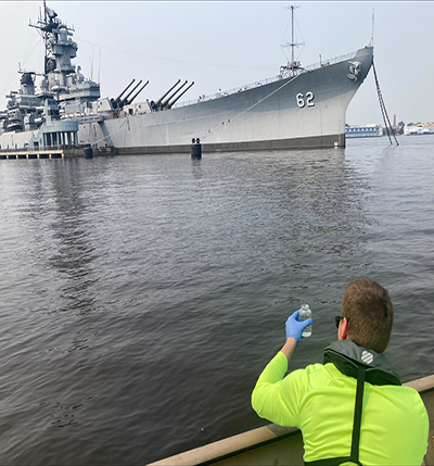 DRBC Water Quality Intern Kyle McAllister collects a water sample to monitor bacteria levels. In 2021, boat-based collection in five transects in the Delaware Estuary complemented the DRBC's shore-based bacteria monitoring program. Photo by DRBC.