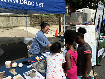 DRBC Water Resource Engineer Dr. SeungAh Byun, P.E. talks with kids who stopped by our table at Sen. Haywood's Back to School event. Photo by DRBC.