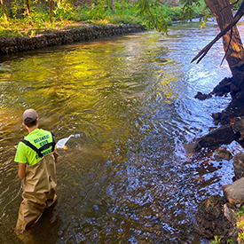 DRBC staff collects a sample to monitor microplastics ocncentrations from the Assunpink Creek. Photo by DRBC.