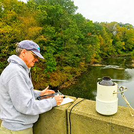 DRBC staff collects a sample from the Neshaminy Creek to monitor for microplastics. Photo by DRBC.