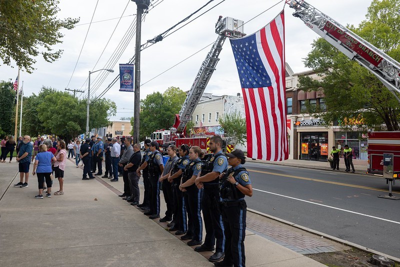 Long Branch police officers standing in front of American flag at Long Branch 9/11 Memorial.