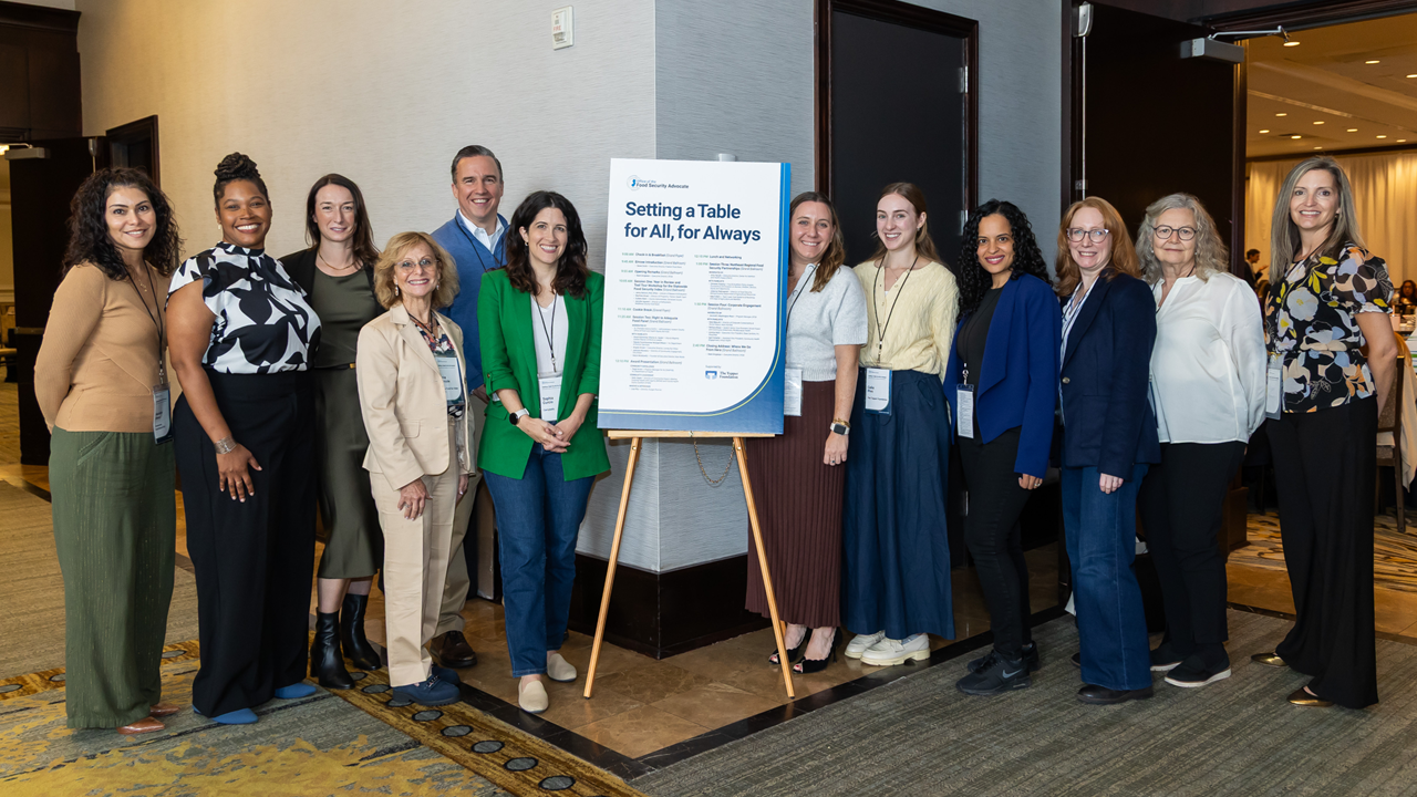 members next to a sign that reads Setting a Table for ALL, for Always