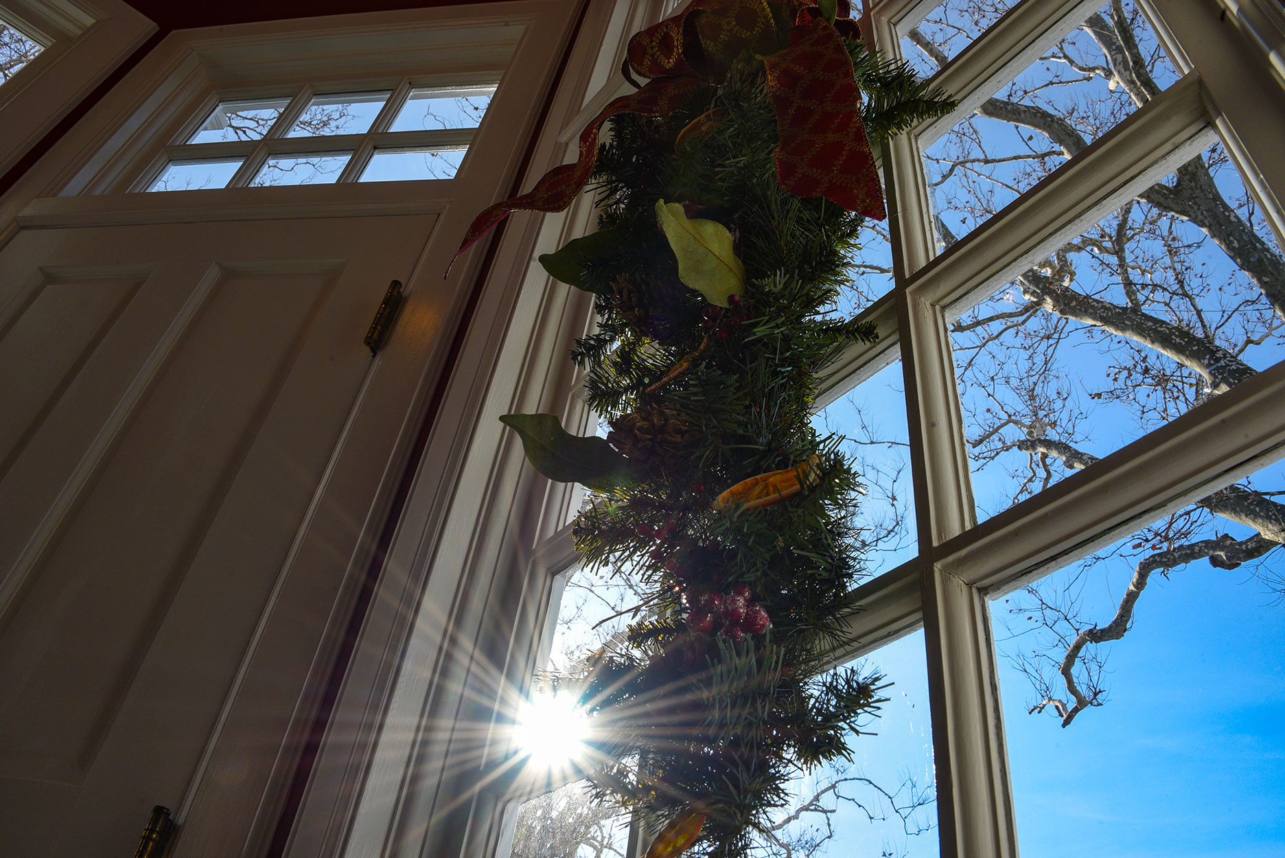 A view of a vestibule window just outside the Governors Study. A natural arrangement hanging in the window, sunlight streaming through