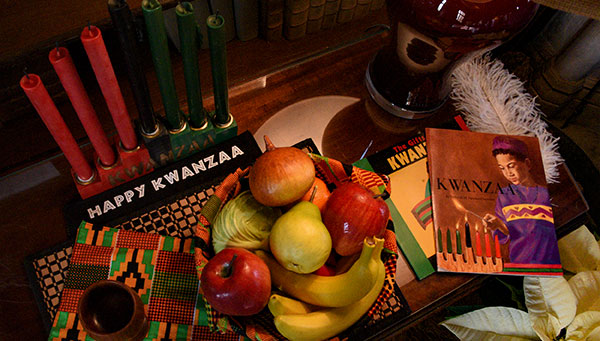 photo - In the Library, a close view of a Kwanzaa display including fruit, traditional candles, books and a single feather.