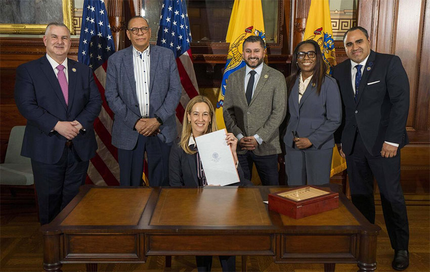 Governor surrounded by NJ state official signing bill