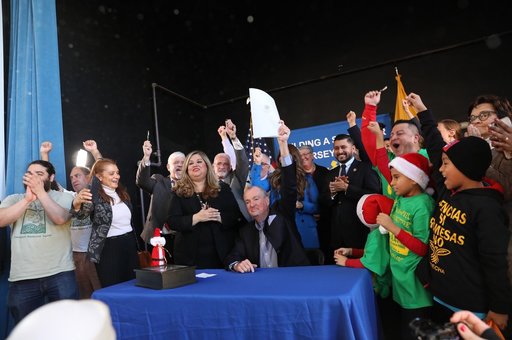 Governor Murphy sitting at a table with a crowd behind him