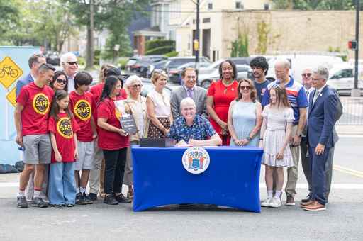 Governor Murphy sitting outside at table with children and adults on the background