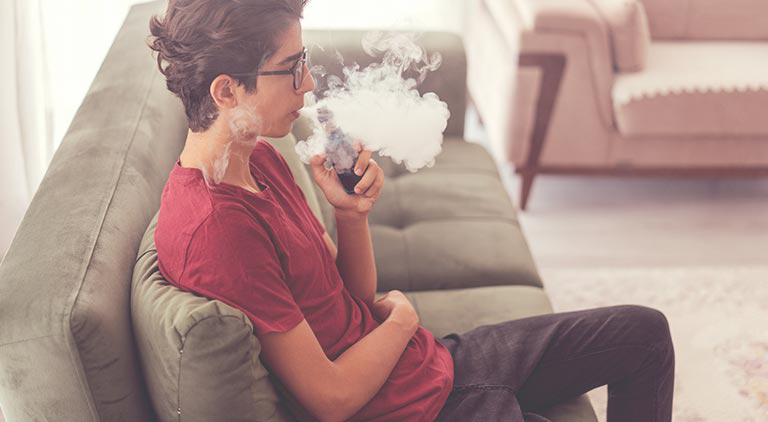 Photo: Teenager sitting on couche vaping