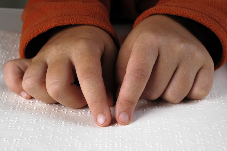 Hands of a child on the book for blind