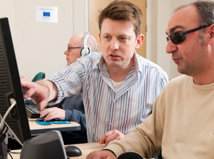 Blind person being assisted while using a computer