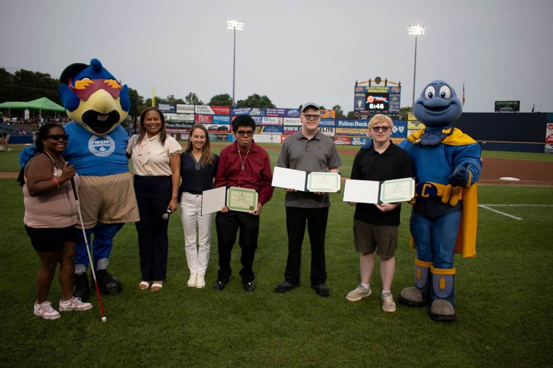 People posing for a picture with awards at the stadium