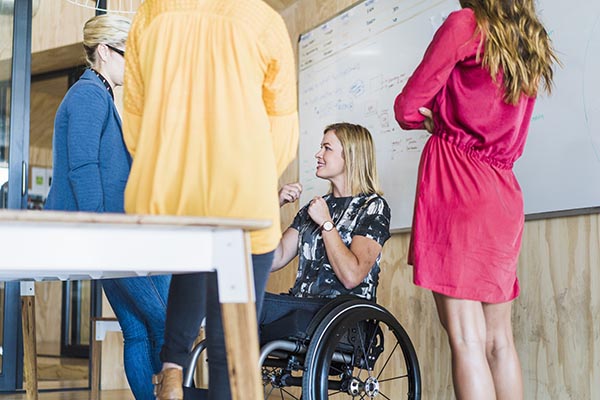 coworkers talking in a meeting, including a woman in a wheelchair