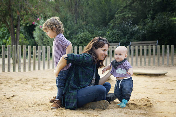 a nanny with two children at a park