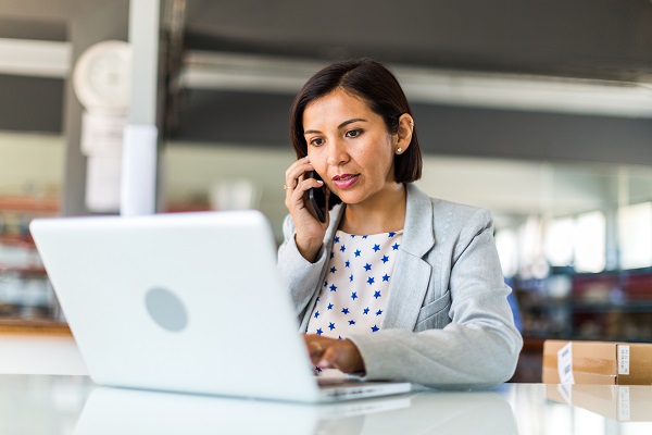 Professional on laptop and phone at desk 