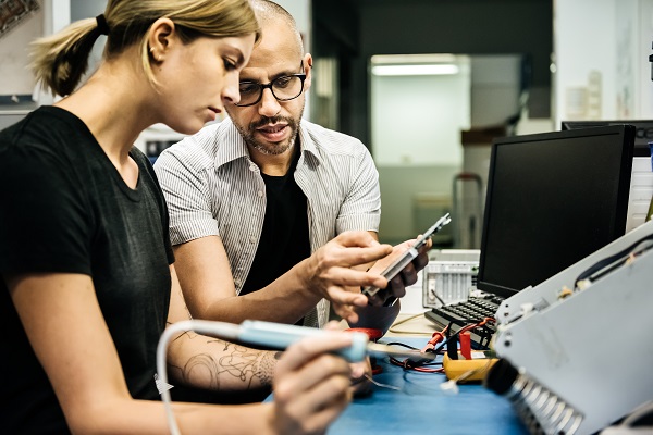 Technician guiding trainee in workshop.