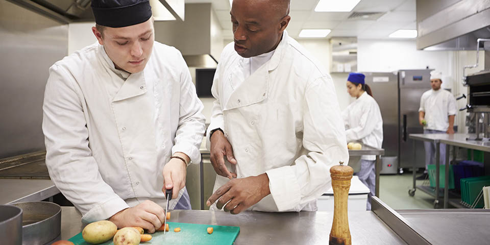 young worker receiving on-the-job training at restaurant