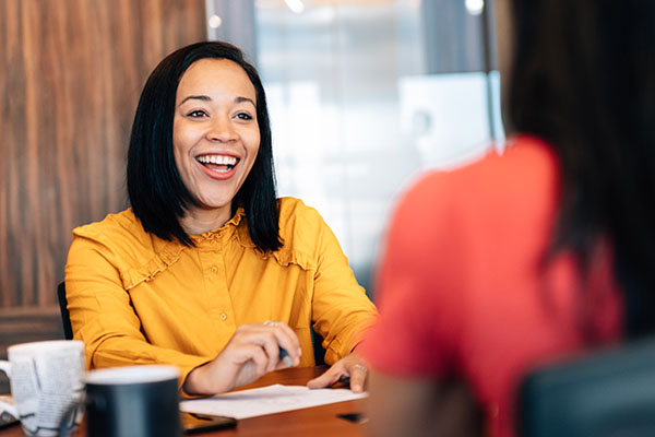 Woman smiling across table from another woman