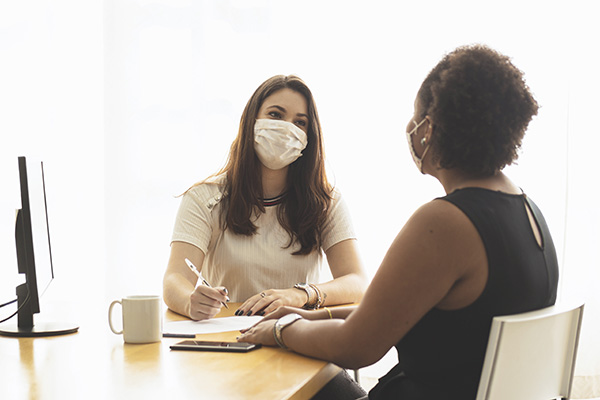 two women wearing face masks in an office for a job interview