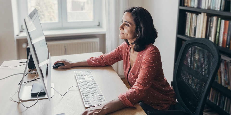 a woman working at a computer at a desk in her home
