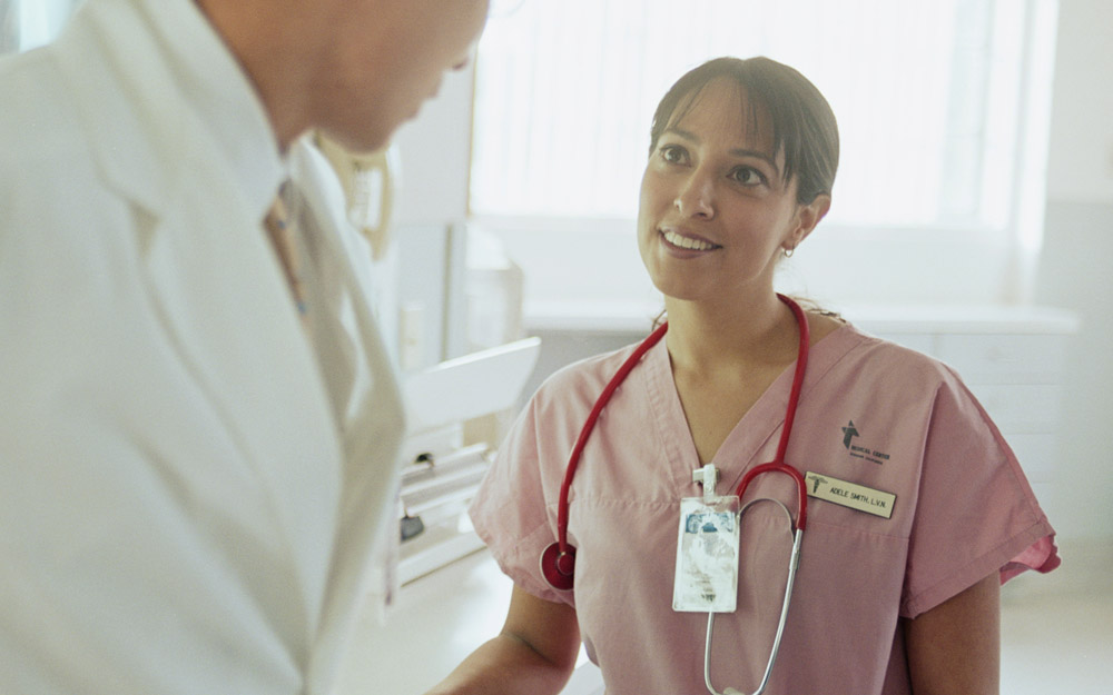 A female nurse or doctor smiling and talking to a male doctor wearing a white coat