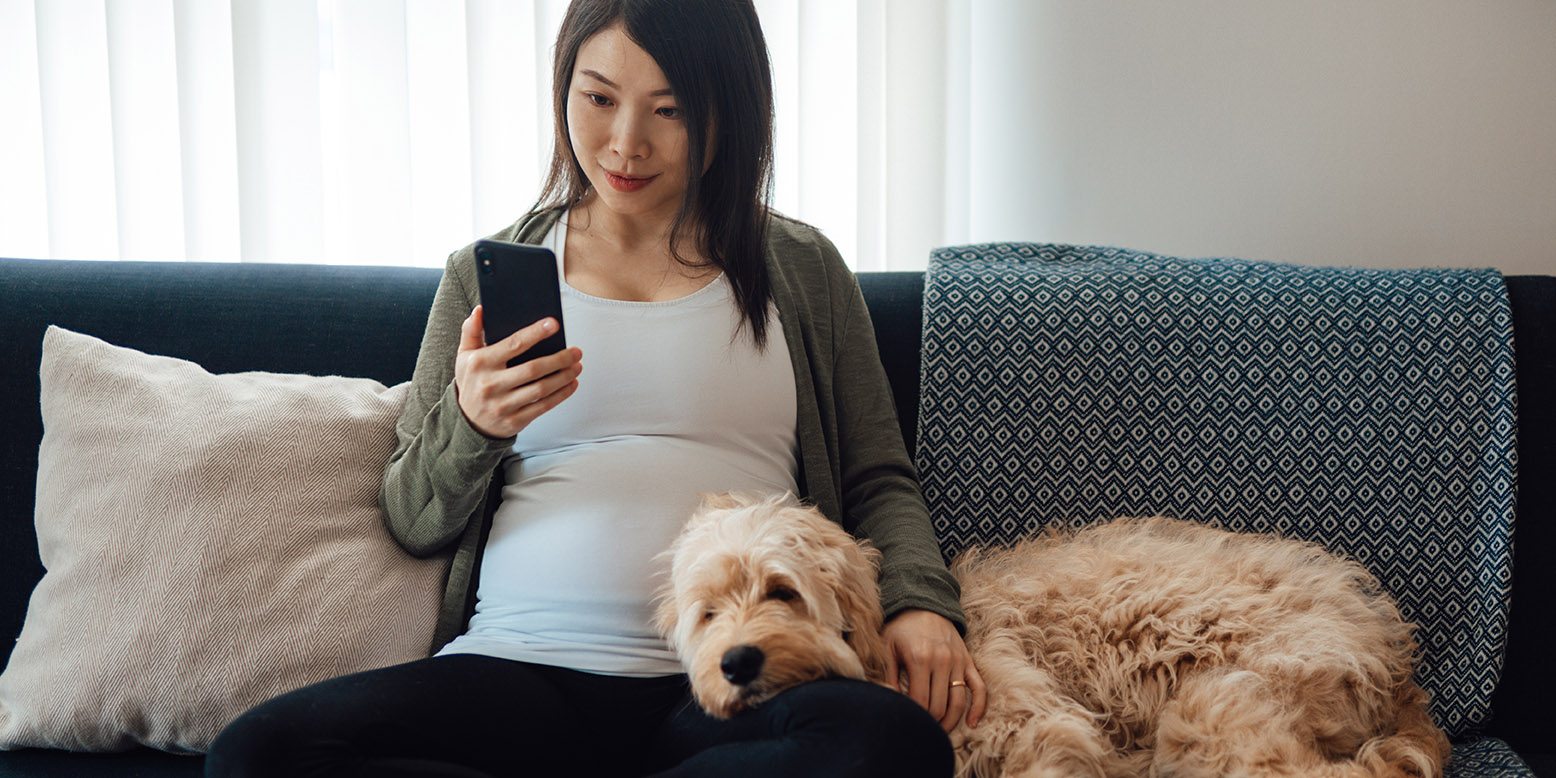 woman sitting on couch looking at her phone
