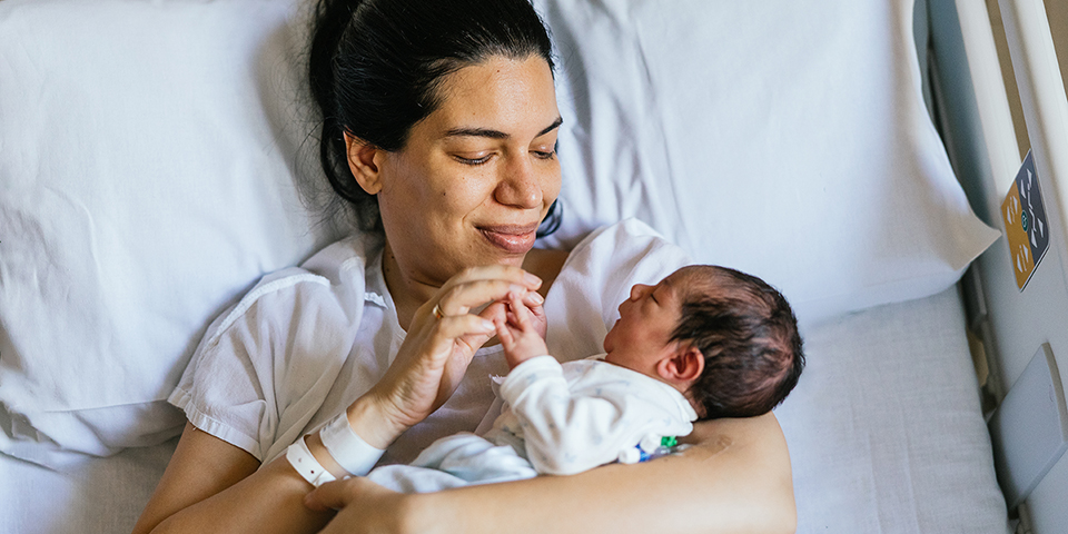a woman in a hospital bed holding and smiling at her newborn baby