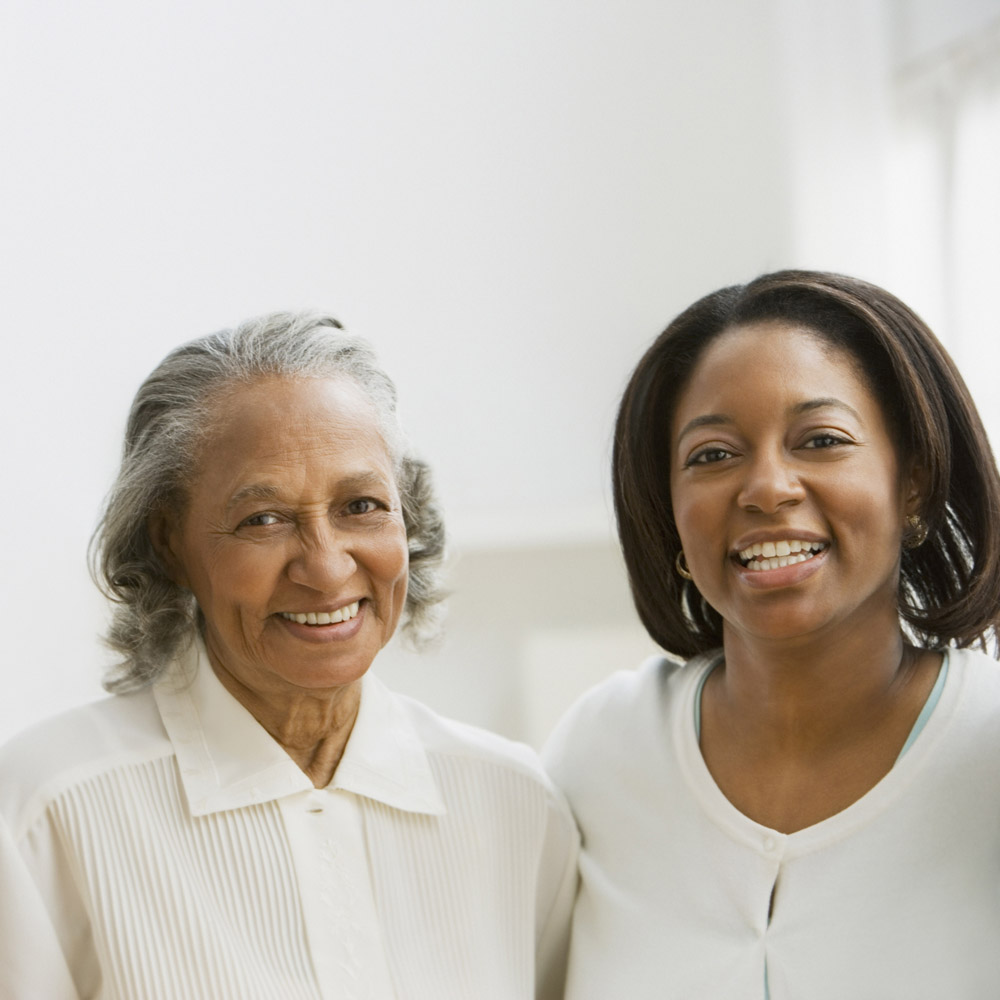An elderly African-American woman and her daughter standing together and smiling
