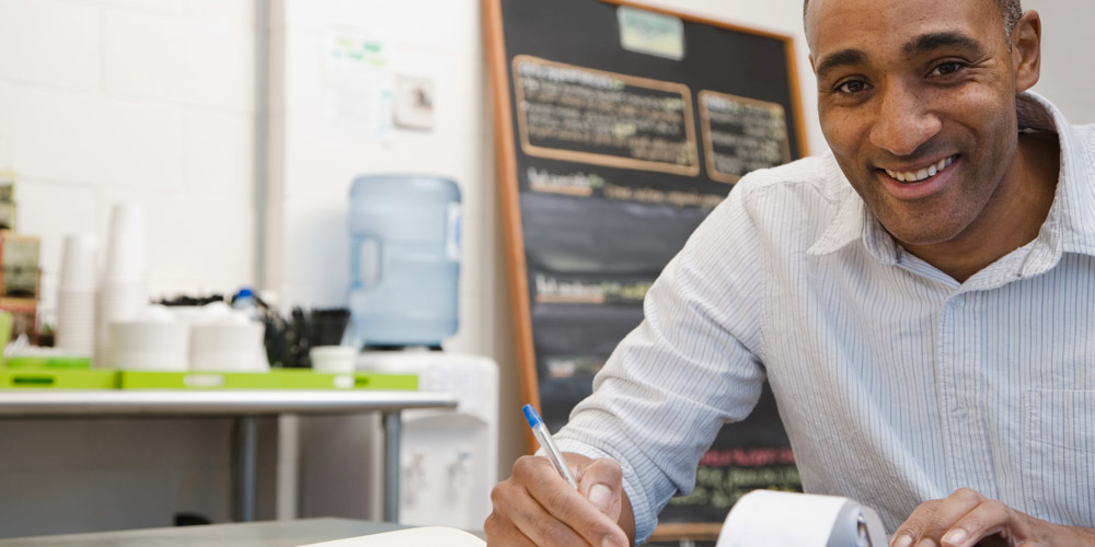 Restaurant manager in the back office doing paperwork, and smiling