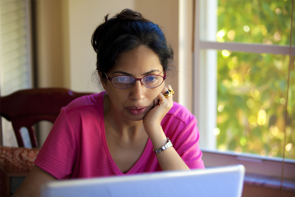 Indian woman working at a laptop computer in her kitchen