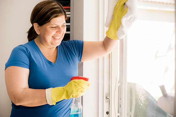 a female house cleaner cleaning a window