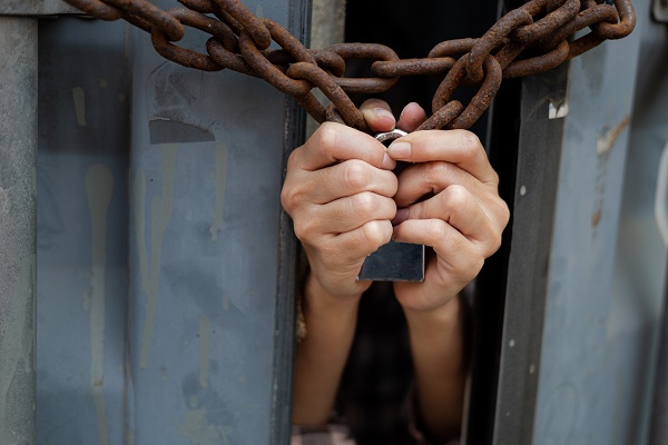 hands reaching out through a locked fence