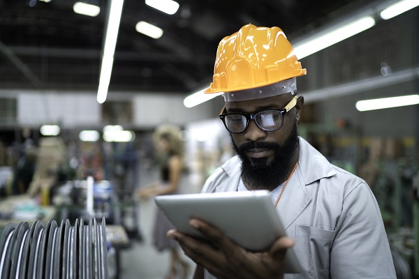 Worker in hardhat looking at tablet