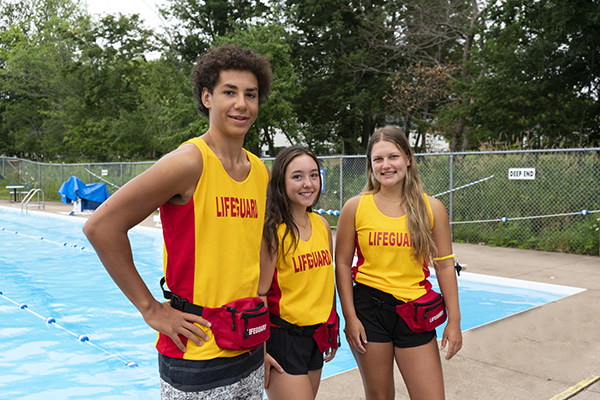 a group of teenage lifeguards standing by a pool