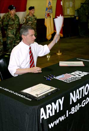 Governor James E. McGreevey displays the legislation that increases minimum pay for Stat Active Duty.