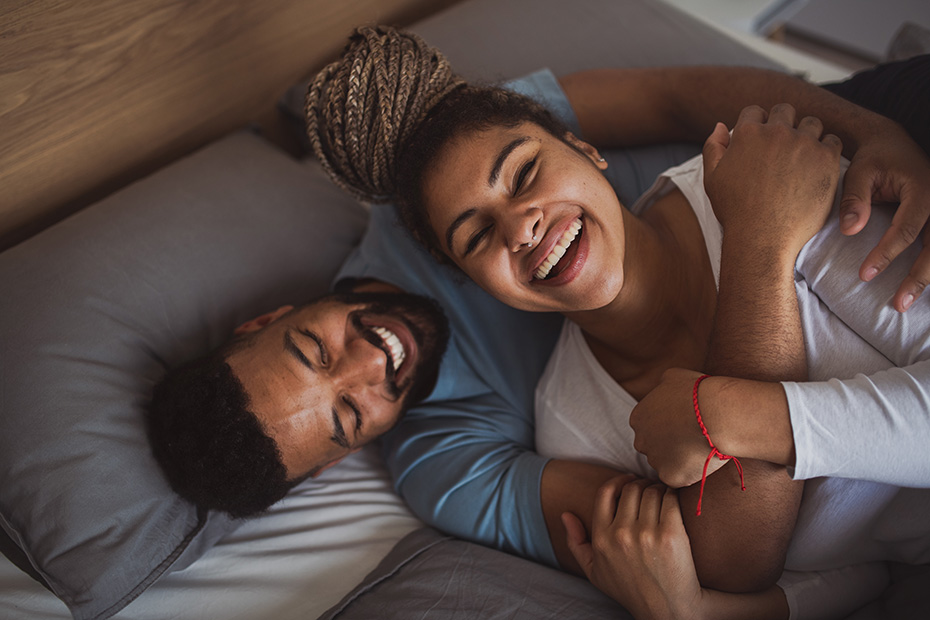 man and woman smiling and laying on each other: photo
