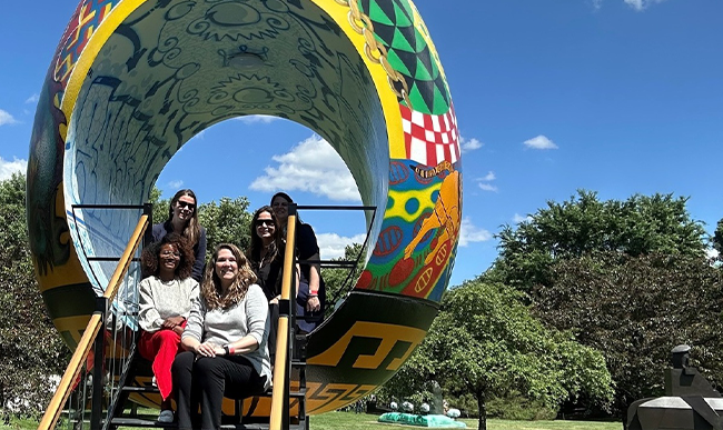 Group of people taking a photo together inside large scale vase sculpture outdoors