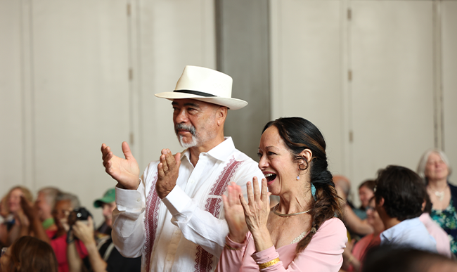 Two people standing up clapping at an event