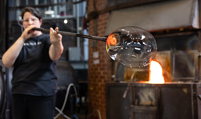 artist blowing glass in studio