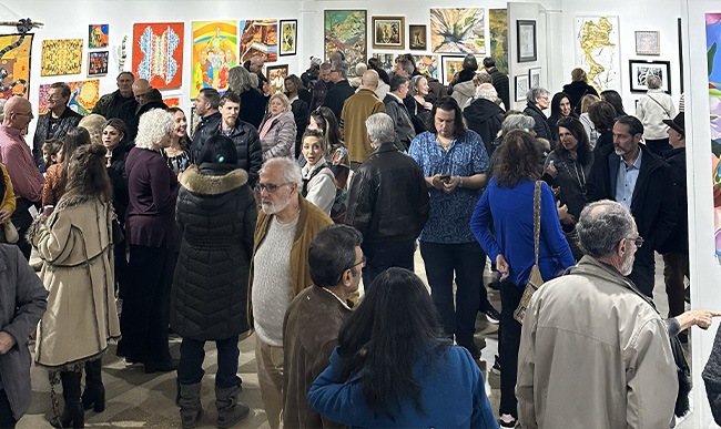 A large crowd in an art gallery during an opening reception.